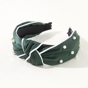 Detail of dark green knot headband with pearl embellishments and white piping trim
