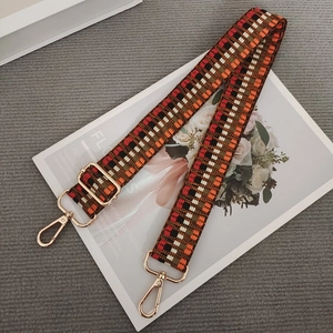 Close-up of woven geometric bag strap with vintage gold metal hooks and adjustable buckle