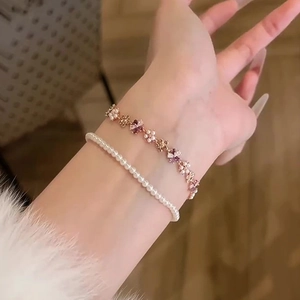 Elegant rose gold flower zircon and pearl bracelet stack for women on a model's wrist
