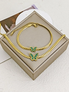 Close-up of golden butterfly jewelry set with green stripes on a premium gift box