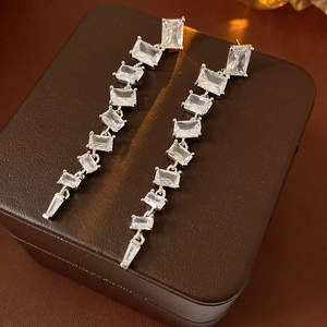 Detailed view of silver tassels earrings with sparkling cubic zirconia on brown leather box