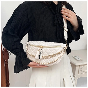 Detail of white quilted crossbody bag with golden chain and wide strap on model