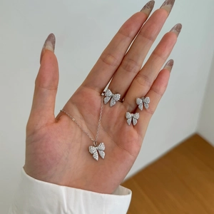 Detailed close-up of 925 silver bow jewelry set with sparkling cubic zirconia on a hand