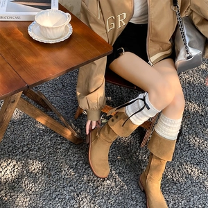 Women's brown suede mid-calf boots with white knitted leg warmers in a street style look
