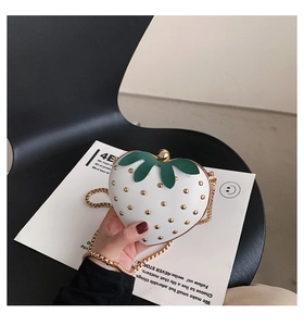 Detailed macro view of strawberry-shaped white handbag with gold studs and leaf decor