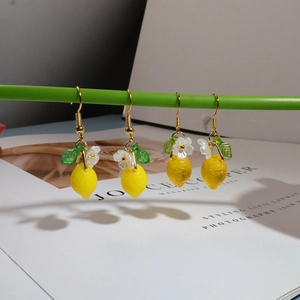 Detail of lemon flower earrings showing resin texture, yellow finish, and green leaf hook