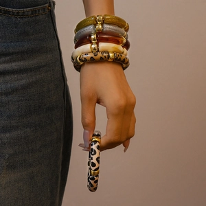 Close-up of stacked acrylic bangle bracelets with leopard print and amber finish