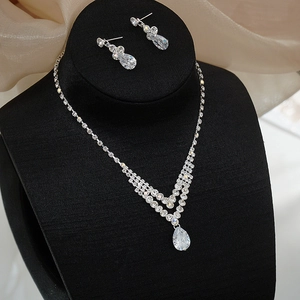 Detailed view of silver necklace and earrings set with pear-cut crystals on black velvet