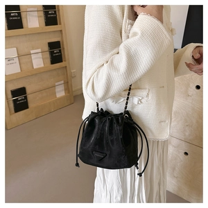 Detail of black drawstring bucket bag with water-ripple texture and chain strap