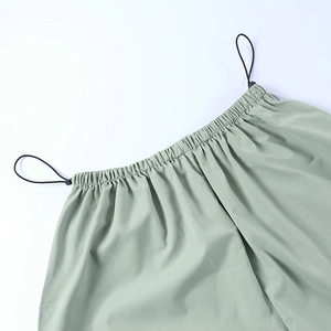 Détail de la taille élastique réglable avec cordon de serrage noir sur pantalon vert