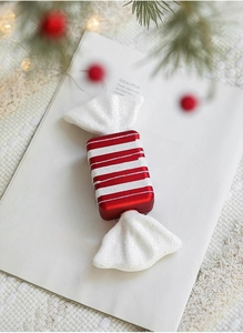 Close-up of red candy-shaped Christmas ornament with white stripes and glitter details