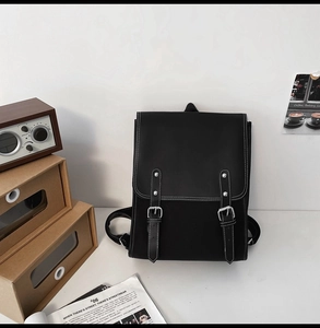 Detail of vintage black PU leather backpack with flap and belt buckles in lifestyle setting