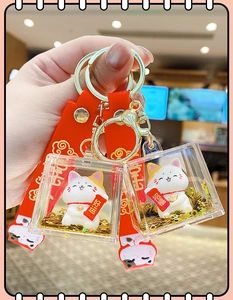 Detail of Maneki-Neko acrylic keychain with golden glitter and red silicone handle