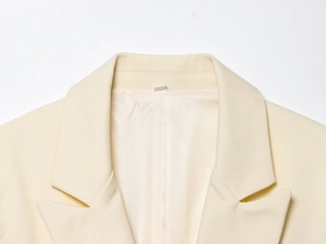 Gros plan du revers en pointe et du tissu texturé sur une veste sans manches crème
