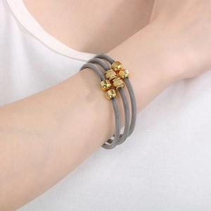 Detail of silver woven mesh bracelet with six textured gold beads on woman's wrist