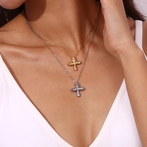 Detail of layered gold and silver cross pendants with unique hammered texture on the chain