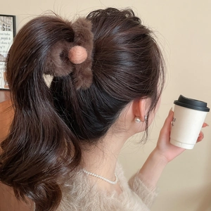 Close-up of brown flocked hair claw with pink pom-pom securing a low ponytail hairstyle