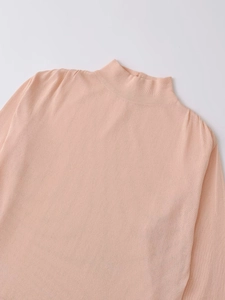 Gros plan du col montant et de la maille fine sur ce pull pour femme de couleur abricot