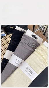 Close-up of three pairs of mesh lace socks in black, dark grey, and creamy white
