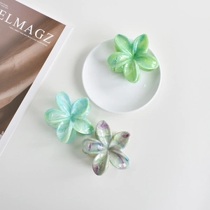 Detailed view of three 7cm acetate plumeria hair claws in mint, blue, and iridescent white