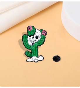 Detailed close-up of a cactus skull enamel pin with pink flowers on a minimal background