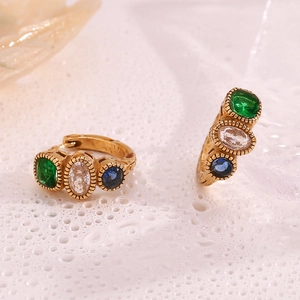 Close-up of vintage 18K gold plated hoop earrings with green, white, and blue gemstones