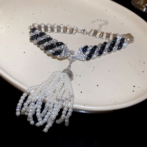 Detail of zircon chain necklace with pearl tassels on a white ceramic dish