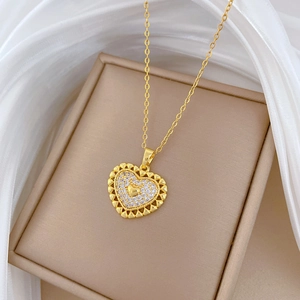 Gold hollow heart pendant necklace with cubic zirconia on a beige jewelry box and silk