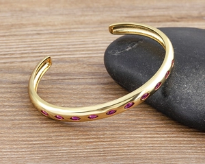 Macro detail of 18k gold plated cuff bracelet with pink oval marquise zirconia on stones