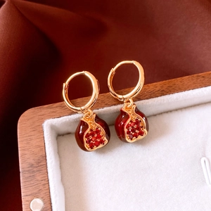 Detail of 18K gold plated pomegranate earrings with red crystals in a velvet box