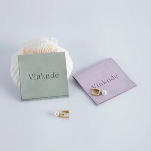 Detail view of pearl geometric earrings alongside velvet jewelry pouches on a seashell