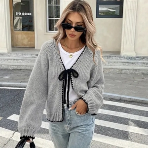 Detail of grey knitted cardigan featuring black ribbon bows and wave trim on V-neck