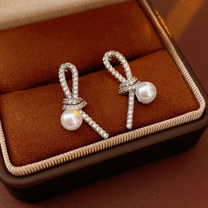 Détail de boucles d'oreilles nœud en argent avec zircons et perles blanches suspendues
