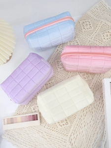 Macro shot of quilted plush cosmetic bags in pastel blue, pink, purple, and cream white