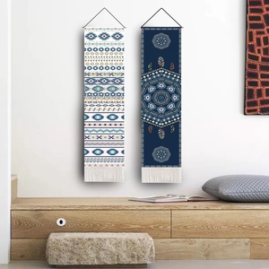 Detail of two boho lunar tapestries with geometric patterns and fringe on a white wall