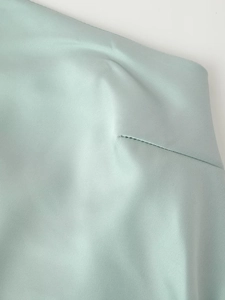 Dettaglio del tessuto satinato verde menta con cuciture fini e consistenza setosa