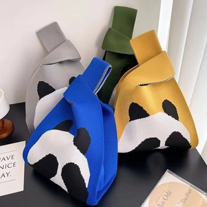 Close-up of knitted panda wrist bags in royal blue, yellow, grey and dark green colors
