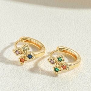 Detail view of 14K gold plated earrings with a colorful zircon cross pendant on white surface