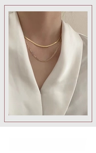Close-up of double layer gold necklace featuring snake chain and paperclip link design