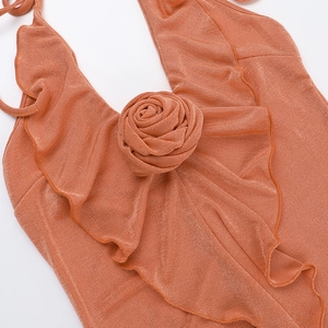 Close-up of caramel orange ruffled dress with fabric rose and metallic knit texture