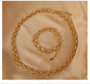 Detail of gold stainless steel necklace and bracelet set on elegant silk background