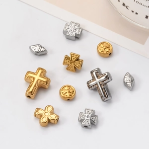 Macro shot of assorted stainless steel spacer beads in cross and shell shapes