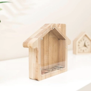 Detail view of wooden house piggy bank with clear acrylic panel and visible coins