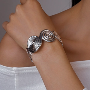Close-up of polished silver spiral geometric cuff bracelet on model wrist