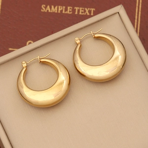 Close-up of golden teardrop hoop earrings with high-polish finish on a jewelry box