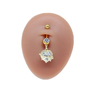 Dettaglio di un piercing all'ombelico a cuore dorato con zirconi indossato su un modello