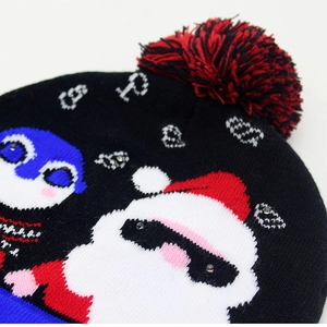 Macro shot of knitted Christmas hat showing fuzzy pompom and Santa Penguin pattern details