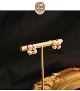 Macro detail of pearl stud earrings in a four-petal flower design on a gold stand