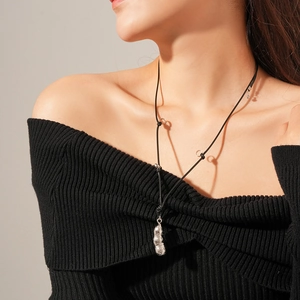 Gros plan d'un pendentif cosse d'arachide sur cordon noir porté par un mannequin