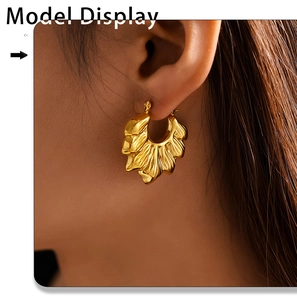 Close-up of model wearing gold pleated wavy hoop earrings with 18k plating
